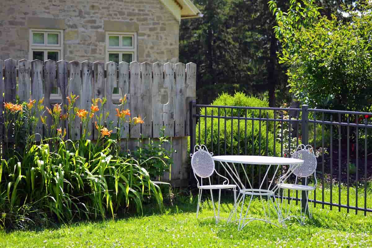 A white cast aluminum table with two chairs in a quiet, manicured garden setting