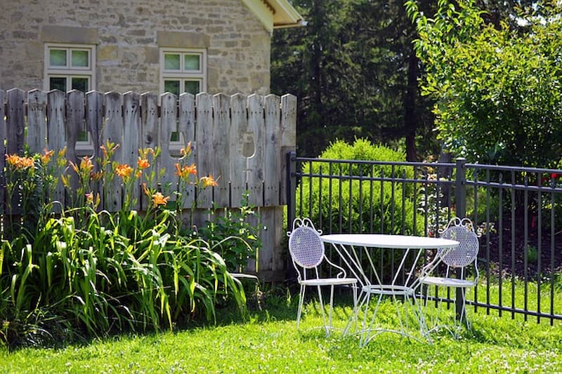 White garden table and two chairs in a calm backyard setting