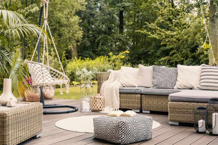 An outdoor living space terrace with a rattan corner sofa, hanging chair and round rug