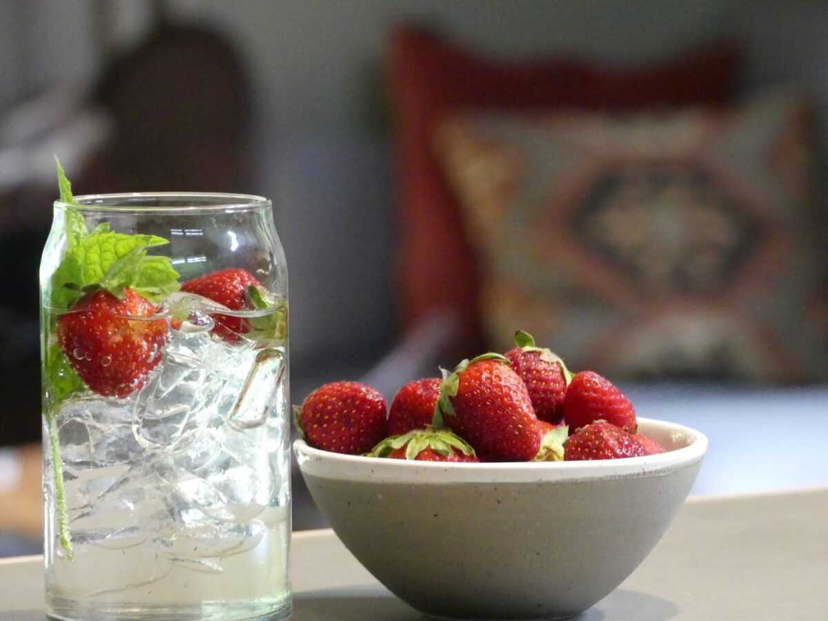 freshly picked strawberries in bowl and on ice in a drink