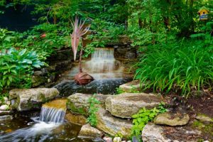 A backyard stream and waterfall with a metal artistic bird art