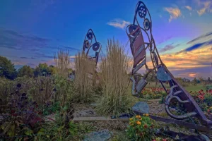 Fifteen feet high Stiletto shoe art, made of used car parts, in a garden at sunrise